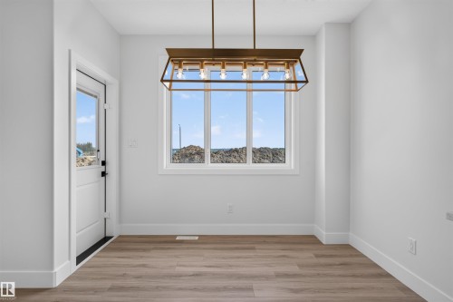 Dining area featuring a large picture window, wood-finish flooring, and a modern rectangular chandelier - 84 Rosa Crescent, St. Albert, AB - Indoor Photo Showing Other Room