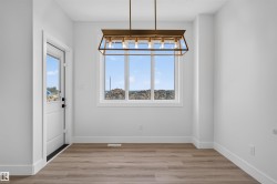 Dining area featuring a large picture window, wood-finish flooring, and a modern rectangular chandelier - 