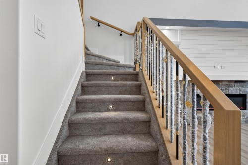 Carpeted staircase with integrated step lighting and a wood handrail with metal spindles - 84 Rosa Crescent, St. Albert, AB - Indoor Photo Showing Other Room