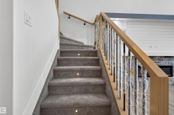 Carpeted staircase with integrated step lighting and a wood handrail with metal spindles - 