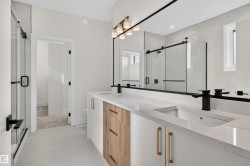 Contemporary bathroom featuring a double vanity with stone countertops, integrated sinks, and matte black faucets - 