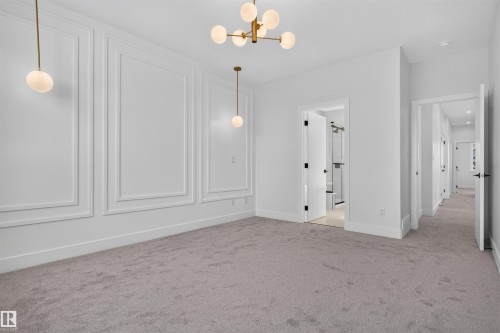 Spacious room featuring elegant wall molding, a modern gold-finish chandelier, and coordinating pendant lighting - 84 Rosa Crescent, St. Albert, AB - Indoor Photo Showing Other Room