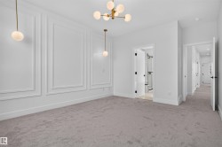 Spacious room featuring elegant wall molding, a modern gold-finish chandelier, and coordinating pendant lighting - 