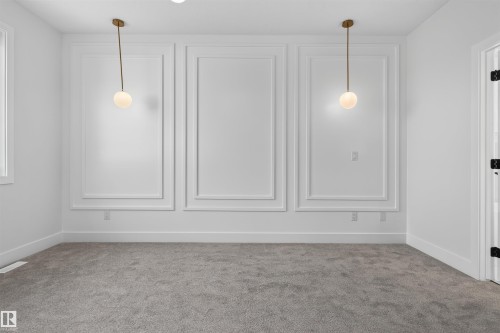 Interior room featuring decorative wall molding, two contemporary pendant light fixtures with spherical glass shades, and light gray carpeting - 84 Rosa Crescent, St. Albert, AB - Indoor Photo Showing Other Room