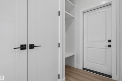 White paneled doors with black hardware, built-in shelving, and wood-finish flooring - 