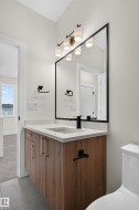 Contemporary bathroom featuring a floating wood-finish vanity with gold-tone hardware, a white countertop with an integrated sink, and a matte black faucet - 