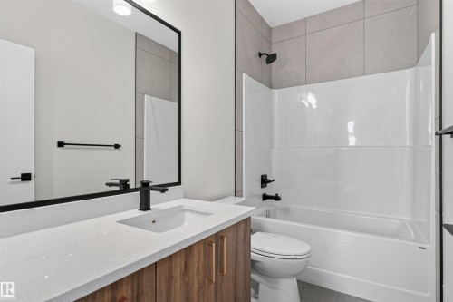Contemporary bathroom featuring a wood-finish vanity with a light-toned countertop, an undermount sink, and matte black fixtures - 84 Rosa Crescent, St. Albert, AB - Indoor Photo Showing Bathroom