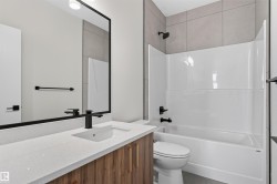 Contemporary bathroom featuring a wood-finish vanity with a light-toned countertop, an undermount sink, and matte black fixtures - 