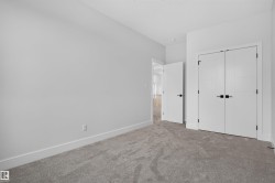 Bedroom featuring neutral gray carpet, white walls, white trim, and a double-door closet with matte black hardware - 