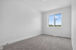Bright room featuring a large window, neutral gray carpeting, white walls, white baseboards, and a ceiling-mounted light fixture - 