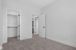 Carpeted room featuring a built-in closet with shelving and hanging rod, white walls, white trim, and modern black hardware - 