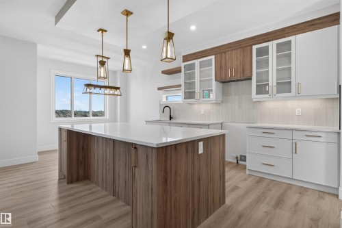 Contemporary kitchen featuring a large island with a light-toned countertop, wood-finish base cabinetry, and brass-toned hardware - 84 Rosa Crescent, St. Albert, AB - Indoor Photo Showing Kitchen With Upgraded Kitchen