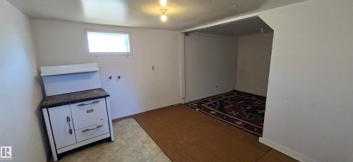Lower-level space featuring a recessed alcove with decorative area rug, a utility sink preparation area, and a casement window - Vegreville, AB - Indoor Photo Showing Other Room