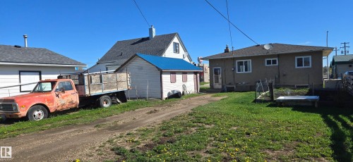 Two distinct residential structures, one with a white facade and gray roof, the other with a tan facade and dark shingle roof - Vegreville, AB - Outdoor
