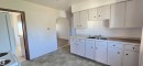 Kitchen featuring white cabinetry with black hardware, a double basin stainless steel sink, and light-toned countertops - Vegreville, AB  - Indoor Photo Showing Kitchen With Double Sink 