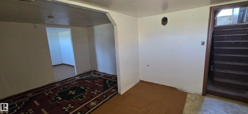 Interior space featuring an arched doorway, white painted walls, and a light fixture - Vegreville, AB - Indoor Photo Showing Other Room