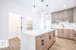 Contemporary kitchen featuring a waterfall island with white marble-finish countertops, wood-finish cabinetry, and matte black hardware - 