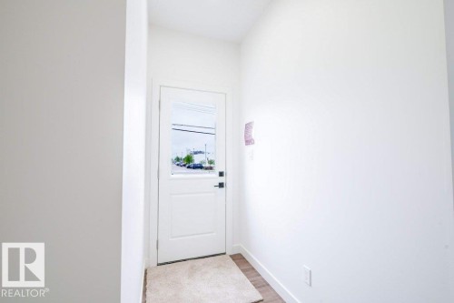 Entryway featuring a white paneled door with integrated glass, wood-finish flooring, and crisp white walls - 5211 104A Street, Edmonton, AB 