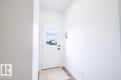 Entryway featuring a white paneled door with integrated glass, wood-finish flooring, and crisp white walls - 