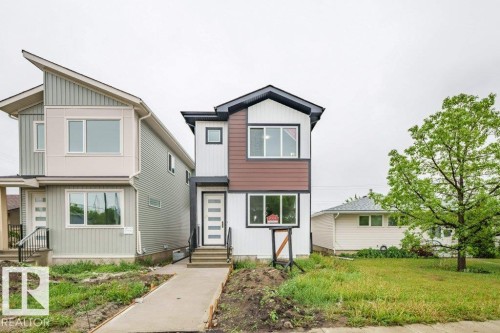 Modern architectural style featuring a multi-toned facade, large windows, and a prominent front entrance with a contemporary door - 5211 104A Street, Edmonton, AB 