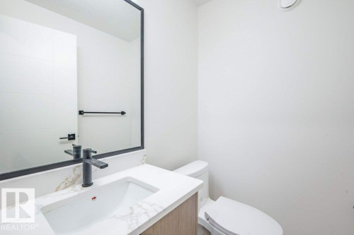 Modern vanity featuring a rectangular undermount sink, quartz countertop with subtle veining, and a matte black faucet - 5211 104A Street, Edmonton, AB 