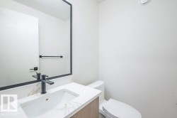 Modern vanity featuring a rectangular undermount sink, quartz countertop with subtle veining, and a matte black faucet - 