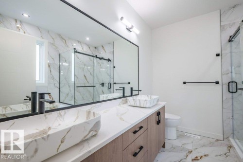 Bathroom featuring a dual vanity with rectangular vessel sinks, matte black wall-mounted faucets, and light wood-finish cabinetry - 5211 104A Street, Edmonton, AB 
