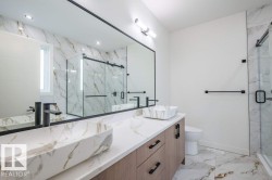 Bathroom featuring a dual vanity with rectangular vessel sinks, matte black wall-mounted faucets, and light wood-finish cabinetry - 