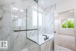 Bathroom featuring a tiled shower enclosure with a clear glass door, built-in bathtub, and matte black fixtures - 