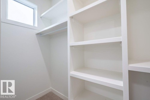 Walk-in closet with built-in shelving, hanging rod, high window, and neutral carpet - 5211 104A Street, Edmonton, AB 