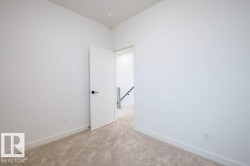 Carpeted room with white walls, baseboards, and a modern white door featuring matte black hardware - 