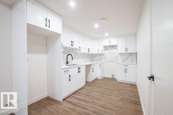 Kitchenette featuring white cabinetry, black hardware, wood-finish flooring, and recessed lighting - 