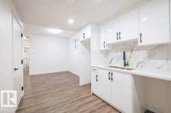 Kitchenette featuring white high-gloss cabinetry, quartz-finish countertops, and a full-height backsplash with a marble-effect pattern - 