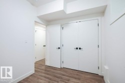 Room featuring wood-finish flooring, white walls, and bright white baseboards - 