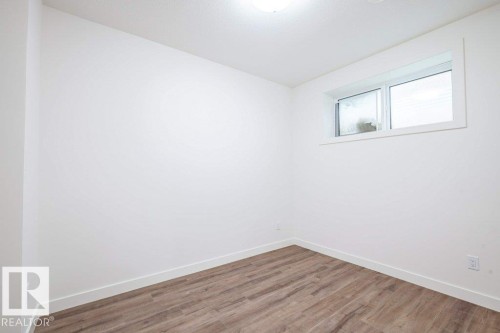 Room featuring white walls, wood-finish flooring, white baseboards, and a single window with white trim - 5211 104A Street, Edmonton, AB 