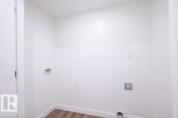 Dedicated utility space featuring wood-finish flooring, white walls, and a modern paneled door - 