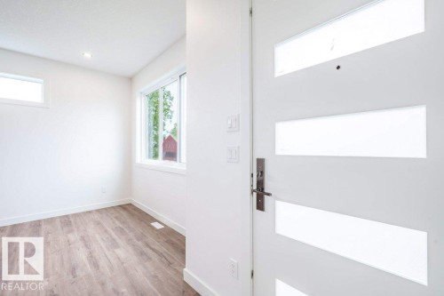Contemporary entry door with frosted glass panels, matte black hardware, and crisp white trim - 5211 104A Street, Edmonton, AB 
