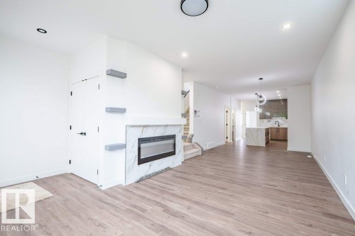 Expansive living space featuring wood-finish flooring, a contemporary fireplace with a marble-look surround, and recessed lighting - 5211 104A Street, Edmonton, AB 