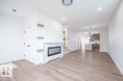 Expansive living space featuring wood-finish flooring, a contemporary fireplace with a marble-look surround, and recessed lighting - 