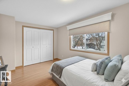 Wood-finish flooring throughout, complemented by a wide window with a neutral roller shade and decorative valance - 14648 54 Street, Edmonton, AB 