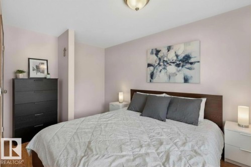 Bedroom featuring wood-finish flooring, a wood-paneled headboard, and soft wall color - 14648 54 Street, Edmonton, AB 