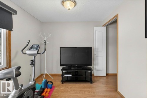 Neutral wall paint, wood-finish flooring, a window with wood trim, and a white interior door - 14648 54 Street, Edmonton, AB 