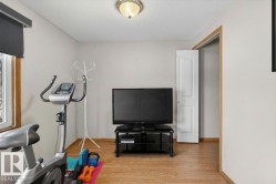 Neutral wall paint, wood-finish flooring, a window with wood trim, and a white interior door - 