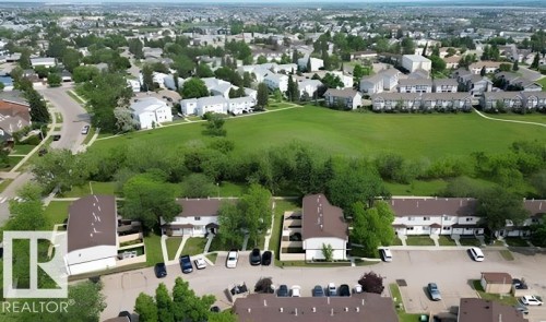 Expansive green space bordered by mature trees, surrounded by residential properties with brown-shingled roofs - 14648 54 Street, Edmonton, AB 