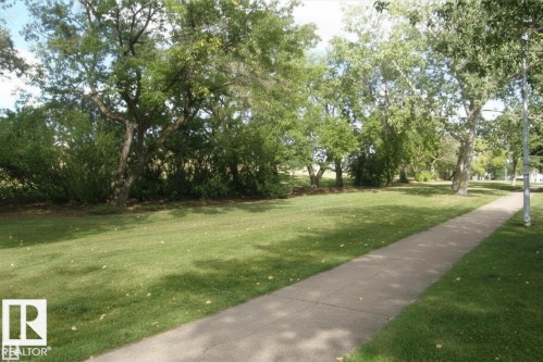 Manicured green space featuring mature trees and a paved pathway - 14648 54 Street, Edmonton, AB 