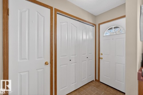 Entryway featuring a white paneled door with an arched transom window, bi-fold closet doors, and wood-finish trim - 14648 54 Street, Edmonton, AB 