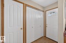 Entryway featuring a white paneled door with an arched transom window, bi-fold closet doors, and wood-finish trim - 14648 54 Street, Edmonton, AB 