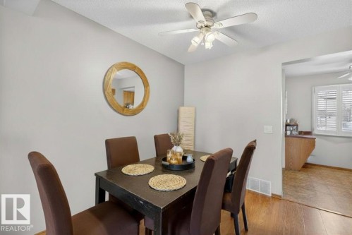 Dining area featuring wood-finish flooring, a ceiling fan with integrated lighting, and neutral wall tones - 14648 54 Street, Edmonton, AB 