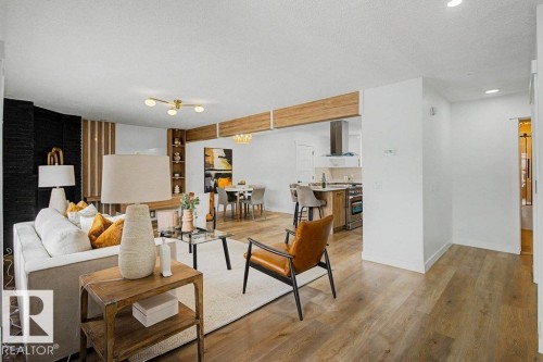 Open-concept living area featuring wood-finish flooring, a contemporary ceiling light fixture, a black accent wall, and a built-in shelving unit - 49 Galloway Drive, Sherwood Park, AB - Indoor