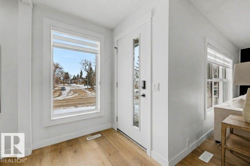 Entryway featuring wood-finish flooring, a white front door with full-length glass inserts, and a large picture window with layered window treatments - 49 Galloway Drive, Sherwood Park, AB - Indoor Photo Showing Other Room